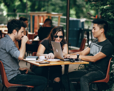 two guys and a girl talking in a restaurant having lunch